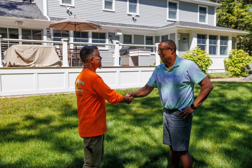 Team member and client shaking hands after tree service