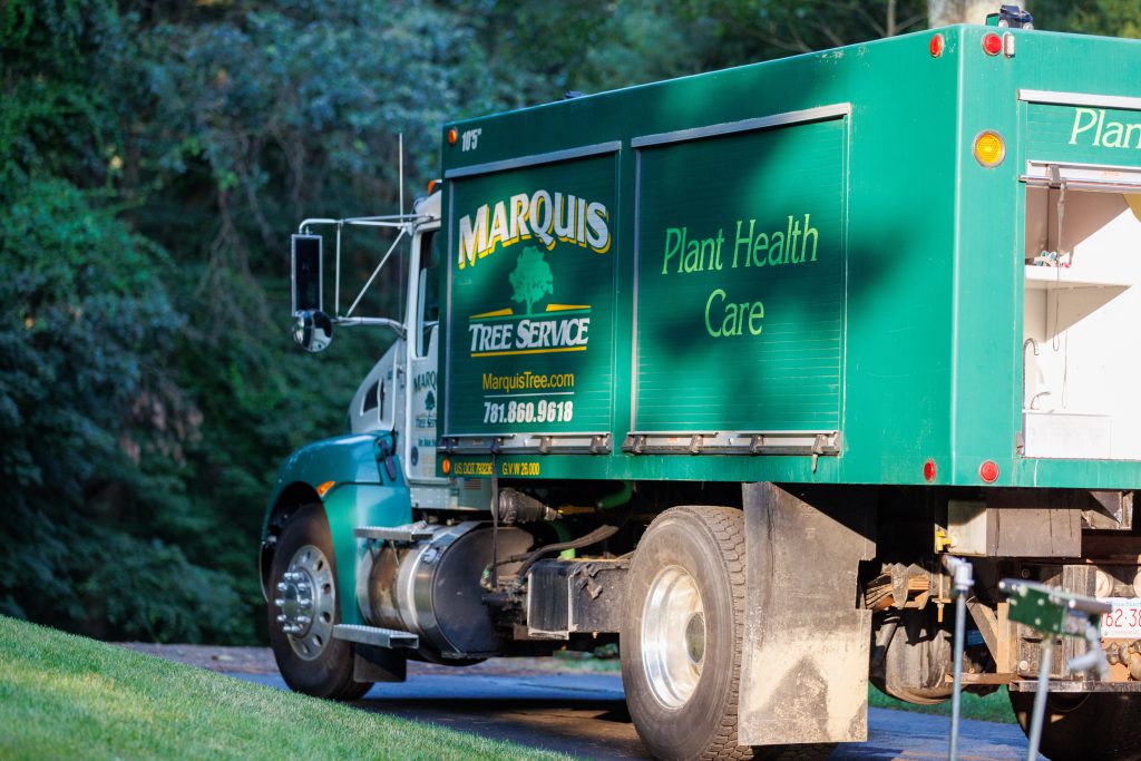 Plant health care truck parked near a driveway